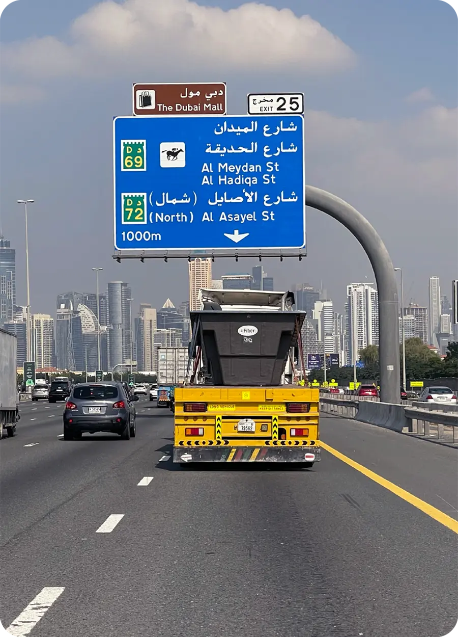 Autopista en Dubái con señal en árabe y skyline al fondo, representando la expansión internacional de Fiber